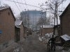 Alleyway lined with small brick and cement buildings.