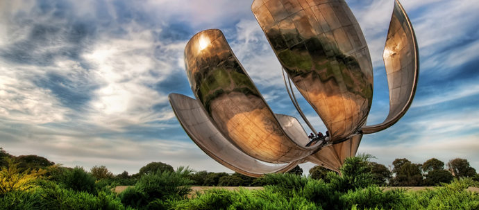 A 75-foot tall metal sculpture of a flower, standing in the middle of a park.