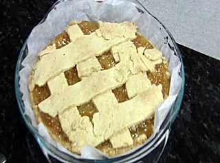 A photo taken above of a pie plate that contains strips of dough and fruit.