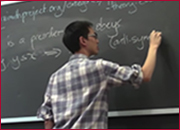 A men standing in front of a blackboard and writing on the blackboard.