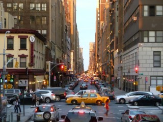 A city intersection with stoplights, automotive traffic, and pedestrians.