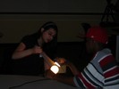 Students hold up a piece of paper to a lit lightbulb.