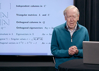 Professor Strang standing behind a podium with a slide screen behind him.