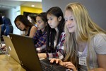 A photo of a group of girls working on their laptops.