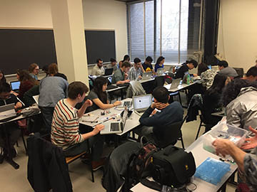 Students sitting in groups watch tutorials with their laptops